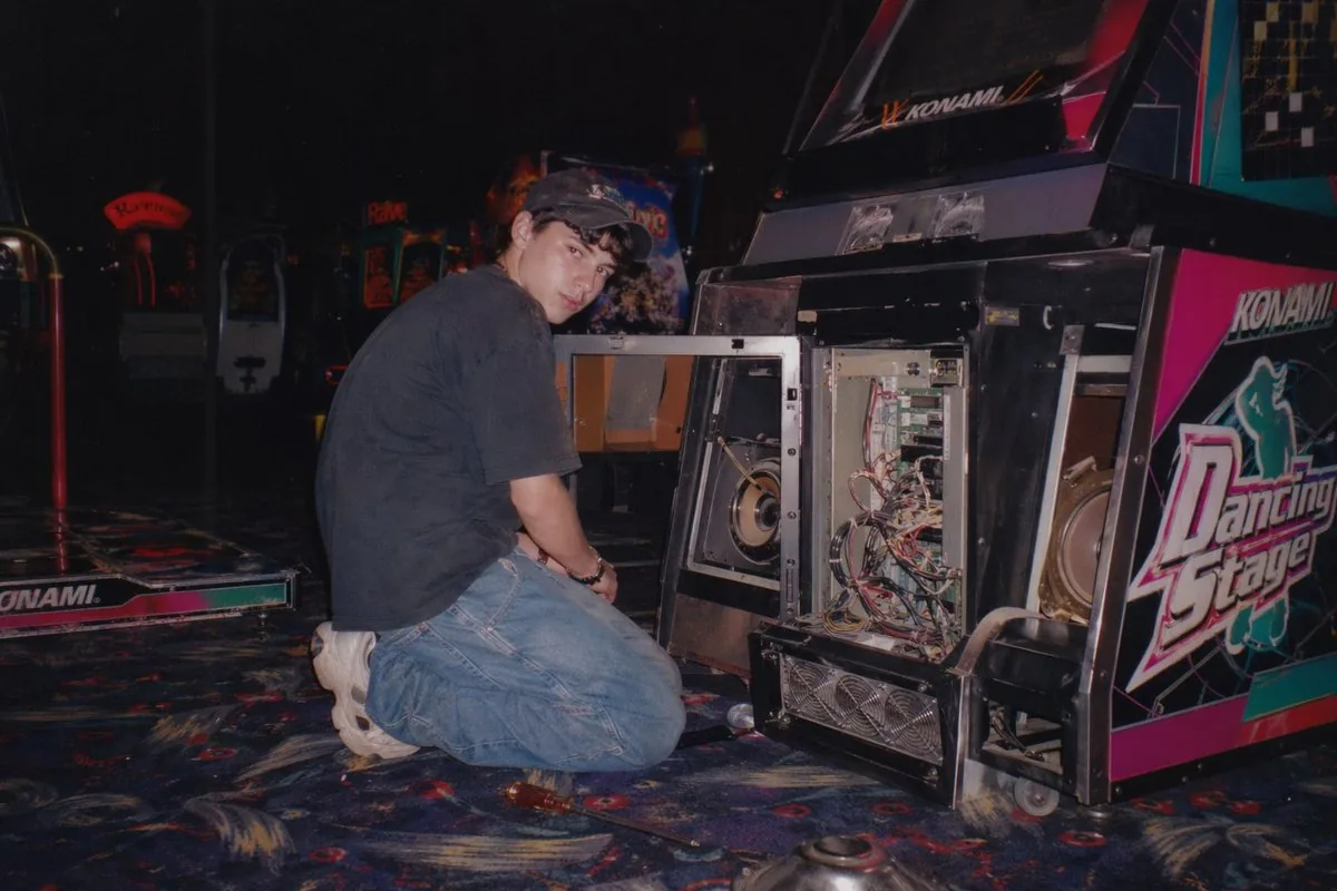 <role>Image generation model</role><context>Dimly lit late-1990s arcade...